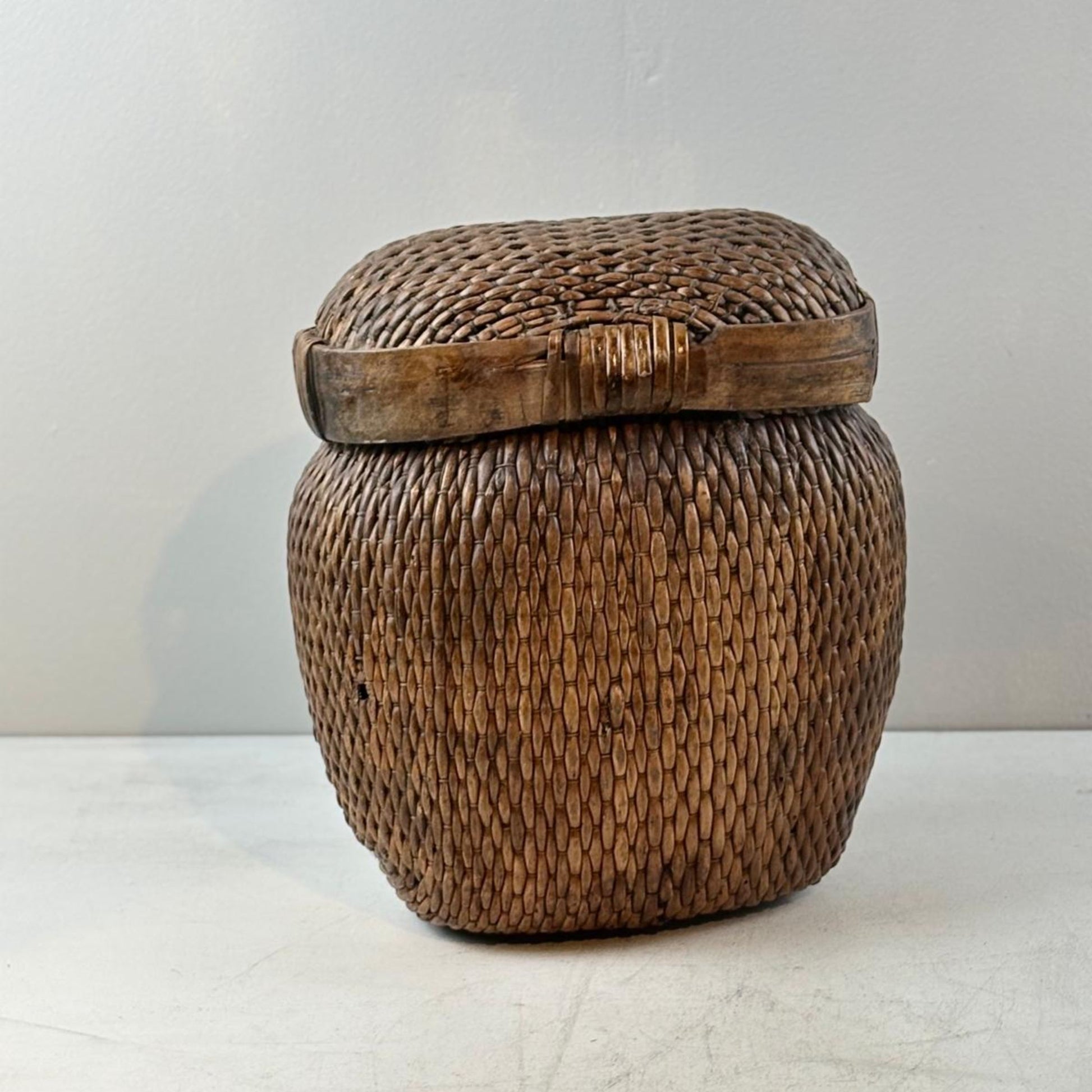 Woven wooden basket with a lid on a white surface