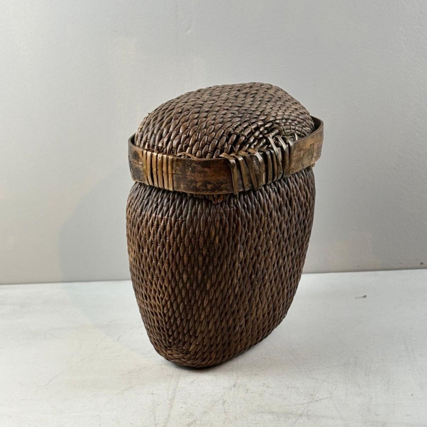 Woven basket with a lid on a light surface and white background